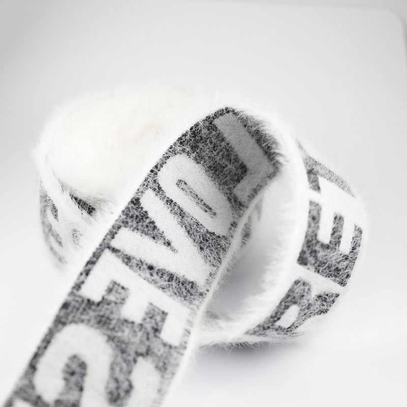 Close view of suede jacquard elastic band showing soft fur-like surface around woven letters