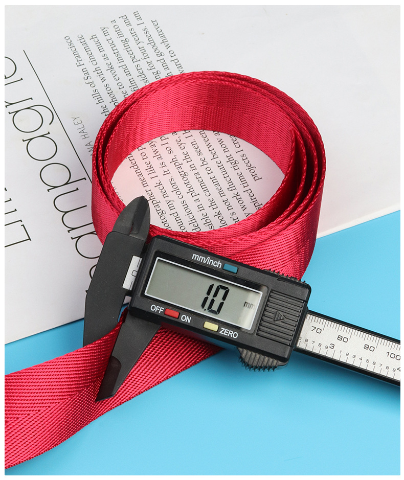 Red imitation nylon herringbone webbing measured with a digital caliper showing a 1 mm thickness